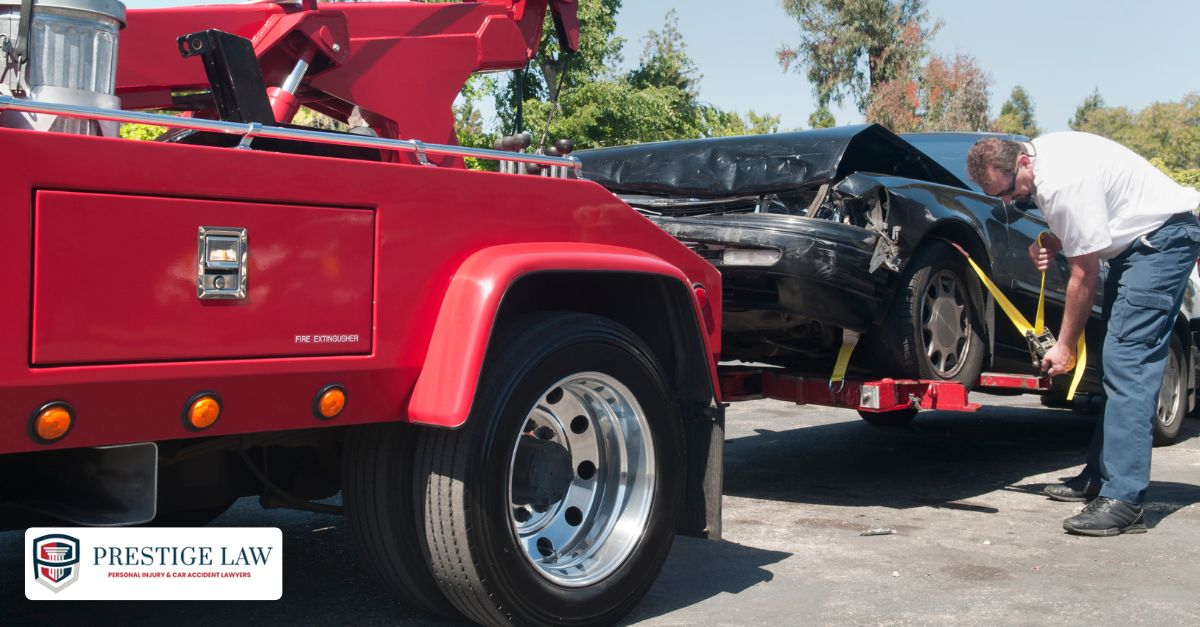 A tow truck loads a damaged car as the driver secures it and the car owner looks on